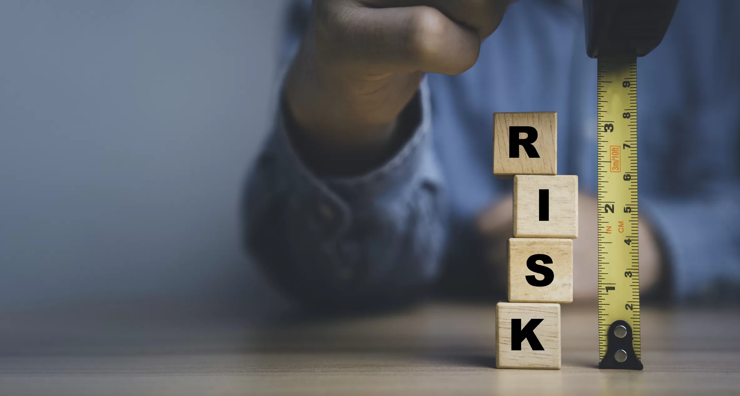 une main tenant un galon à mesurer avec le mot RISK, pour faire référence à l'analyse et la gestion des risques.