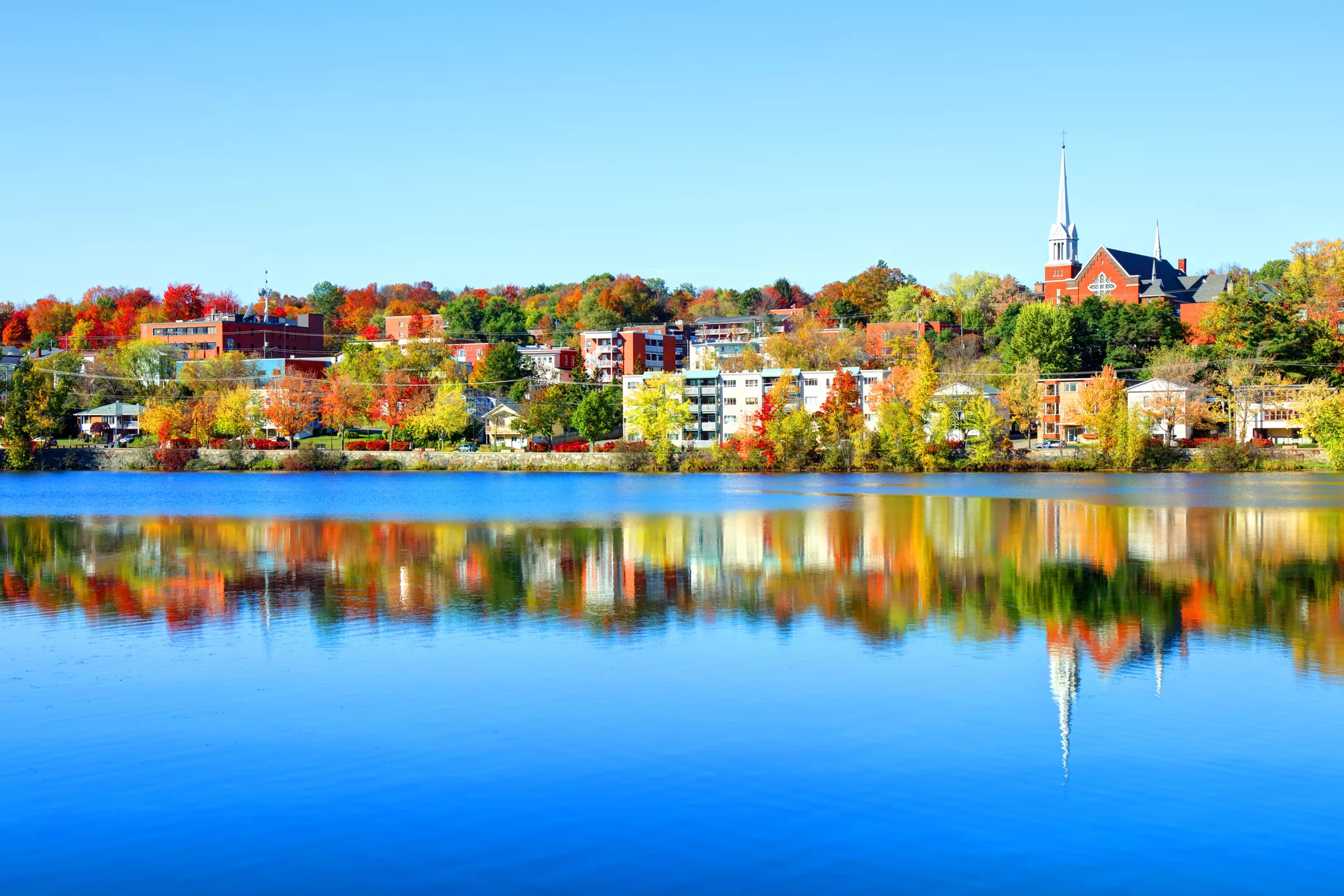 Paysage d'automne de la rivière Magog à Sherbrooke avec maisons, bâtiments et clocher d'église à l'arrière-plan