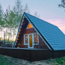 Chalet en bois de forme triangulaire avec lumière à l'intérieur au coucher du soleil