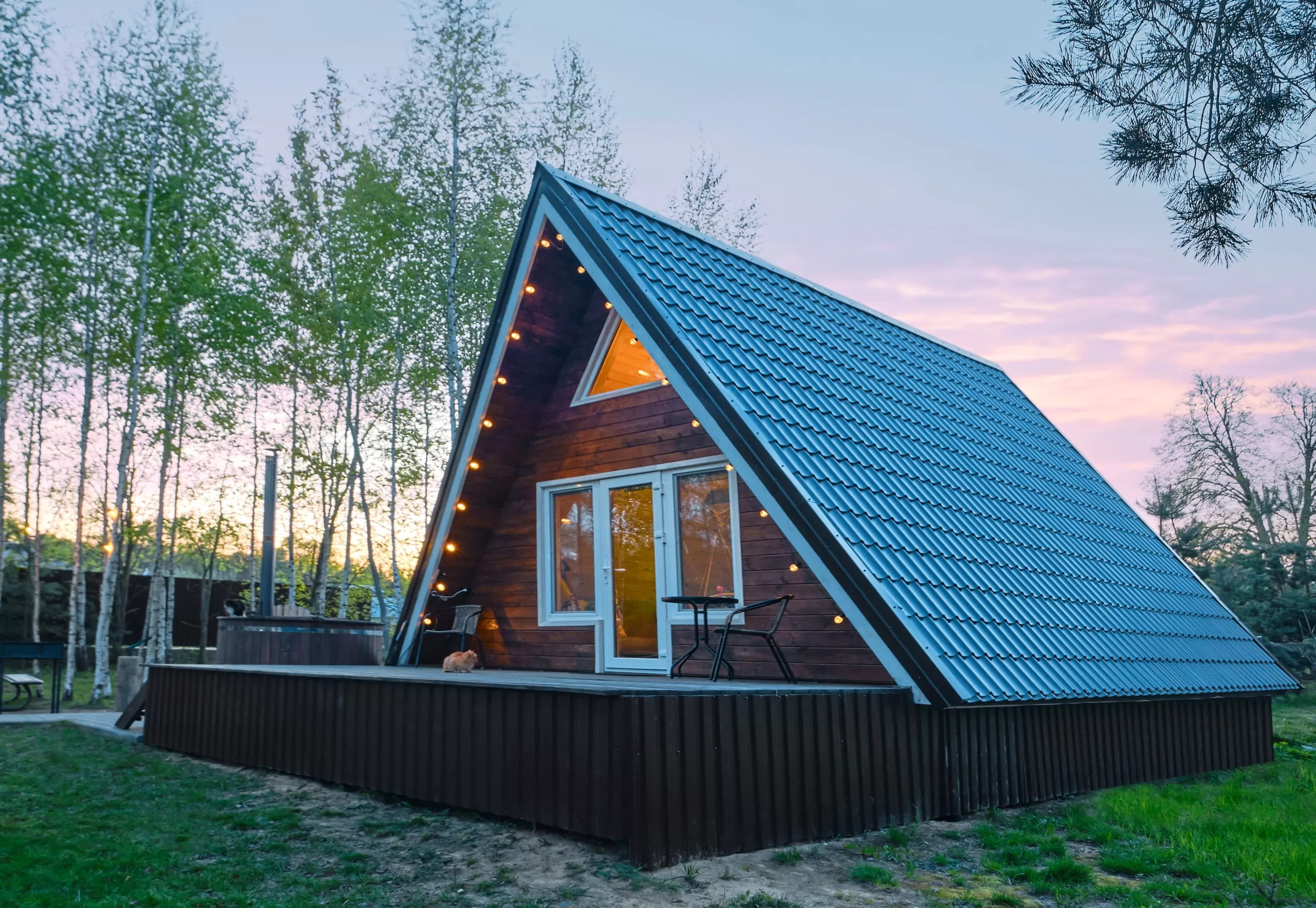 Chalet en bois de forme triangulaire avec lumière à l'intérieur au coucher du soleil