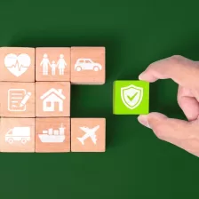 Blocs de bois avec des icônes d'assurance avec une main tenant un bloc de bois rouge, sur fond bleu.