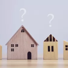 Rangée de petites maisons en bois posées sur une table avec des points d'interrogation au-dessus