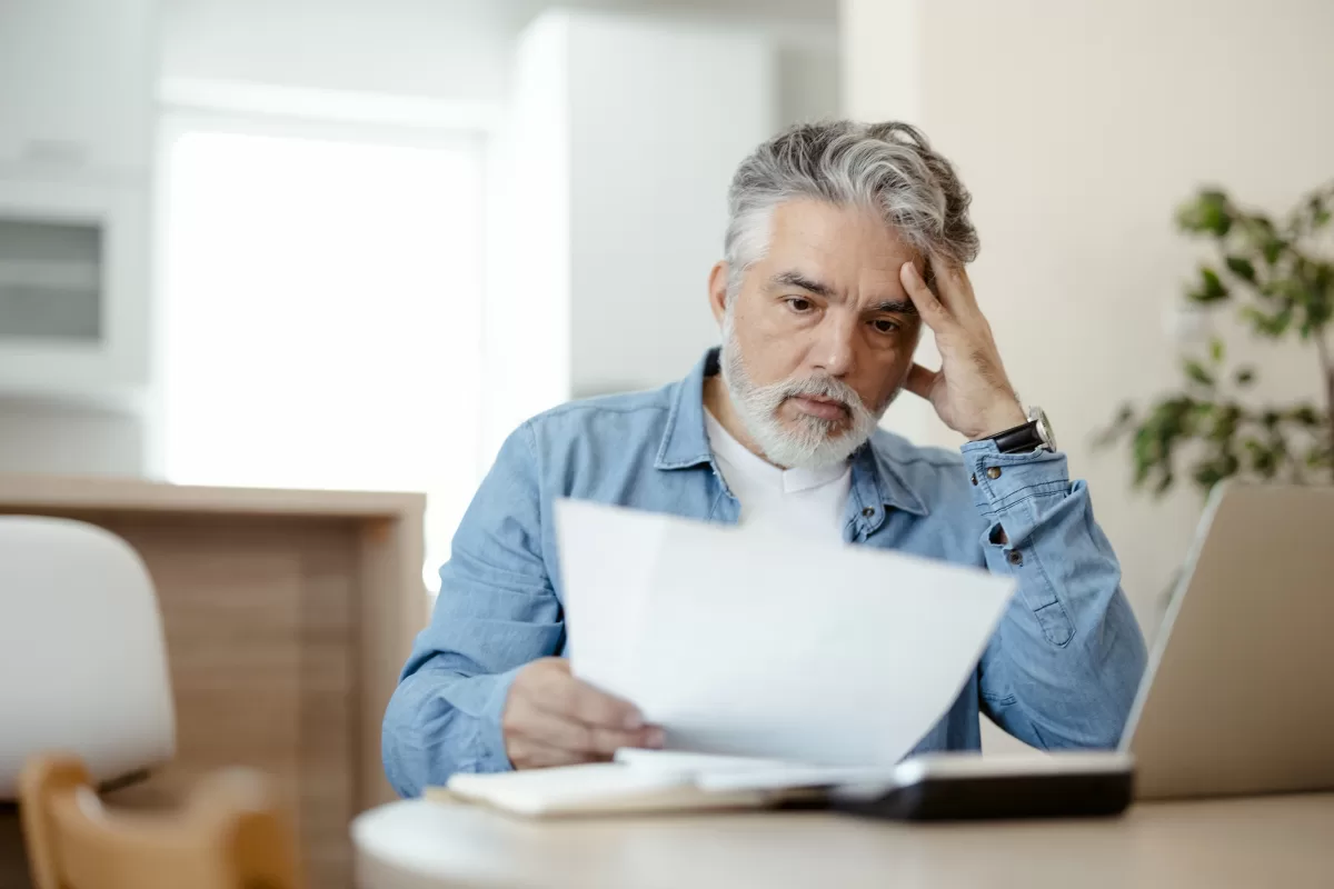 Homme pensif lisant une lettre de refus d'indemnisation de son assurance.